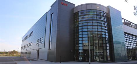 Front of the EPAC building on a sunny day with large windows and a shiny exterior. 
